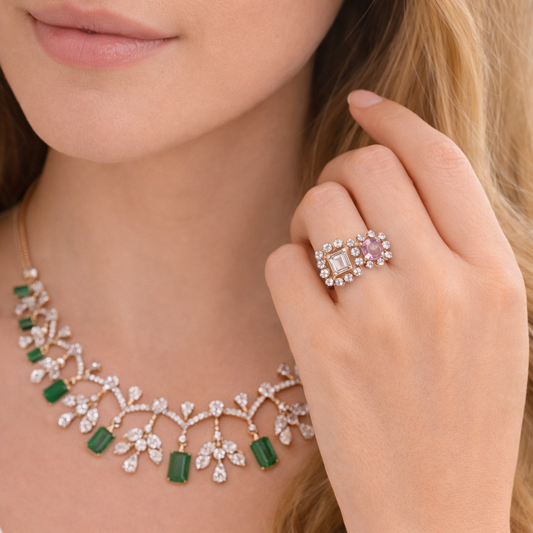 Close-up of a woman wearing a necklace and holding a ring with a pink gemstone.