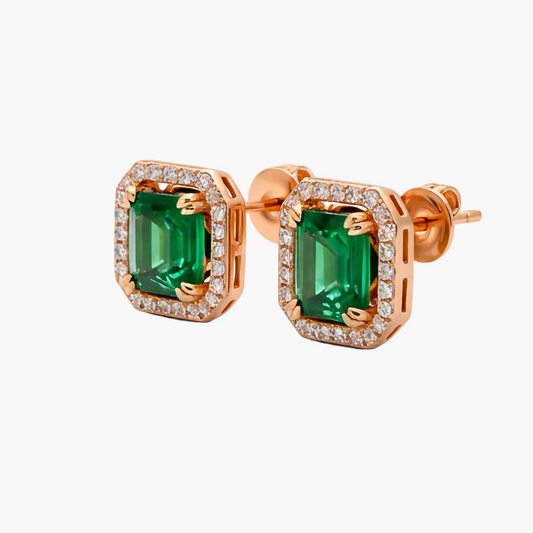 Rose gold earrings with emerald green gemstones on a white background